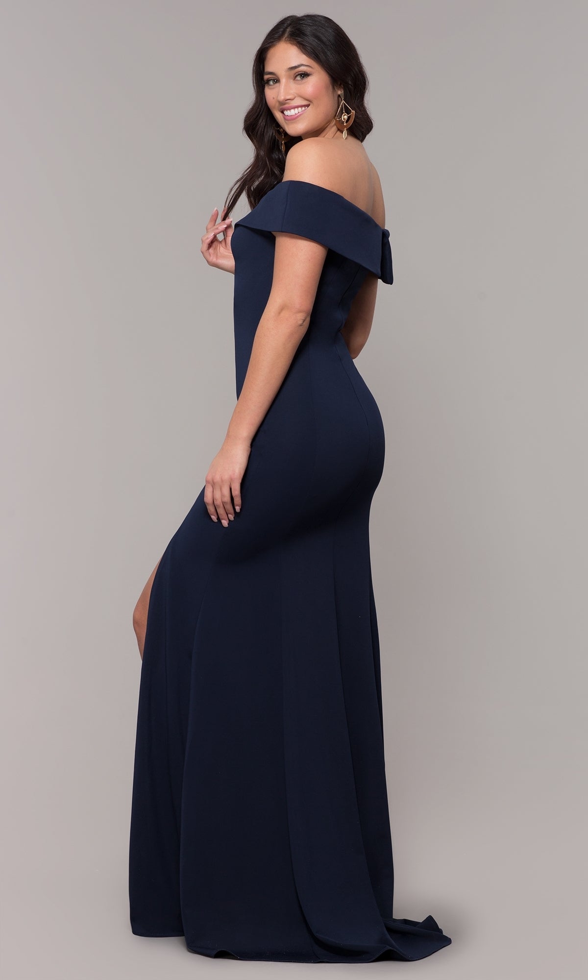 Woman wearing the Classic Off-the-Shoulder Formal Prom Dress 8258, featuring a navy color, floor-length skirt, and side slit, stands against a plain background and smiles at the camera.